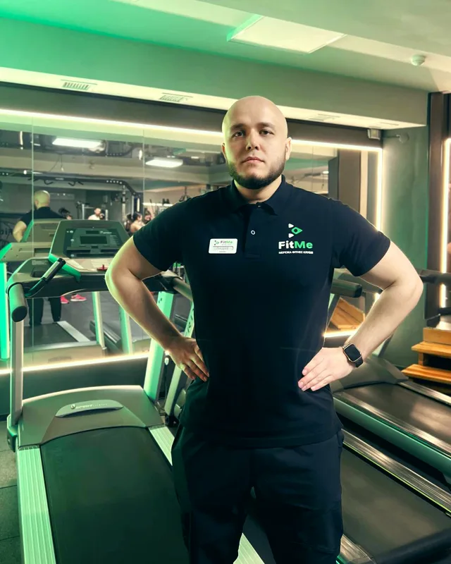 Андрій — тренер FitMe у брендованому поло на тлі кардіо-зони